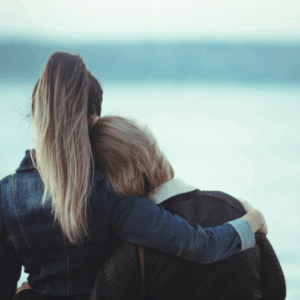 person hugging elderly woman